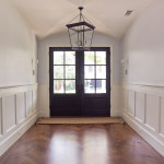 Enter! This stunning entryway has stout mahogany doors, a study in the early American style of housing. Note the painted wood wainscoting, herringbone pattern white oak flooring, and groin vault ceiling.